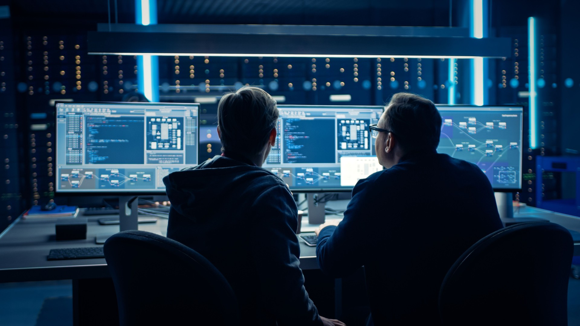 Deux programmeurs informatiques professionnels discutant de la conception et du développement de l'architecture du réseau de données Blockchain affichés sur l'écran d'ordinateur de bureau. Département technique de centre de données de travail avec d